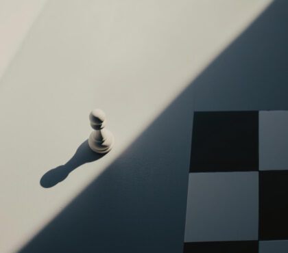 pieza de ajedrez fuera del tablero parcialmente iluminada con fondo de tablero en sombra