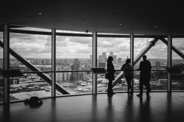 Tres directivos observando la ciudad desde una sala de reuniones de altura